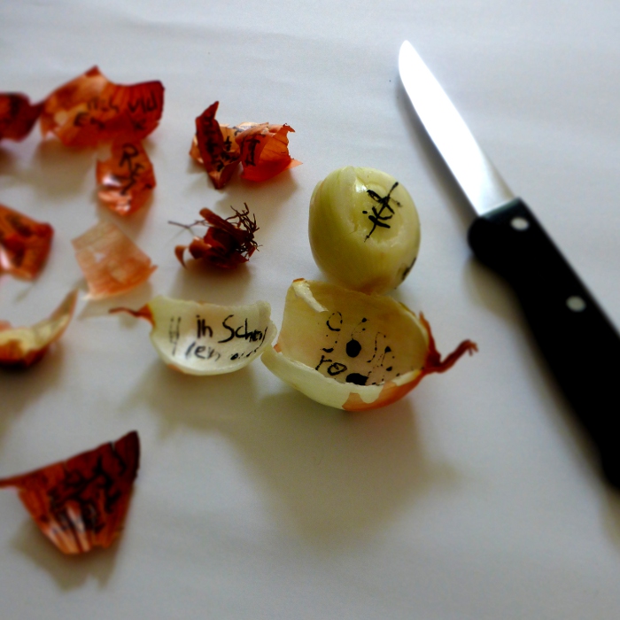 words on onion skins, with kitchen knife. by Ines Seidel